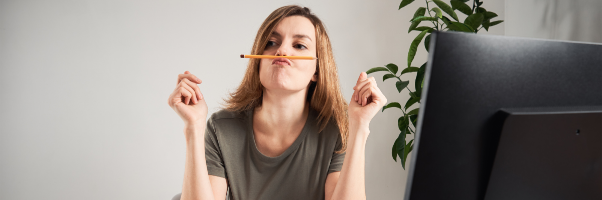a woman sitting at a desk with a pencil in her mouth