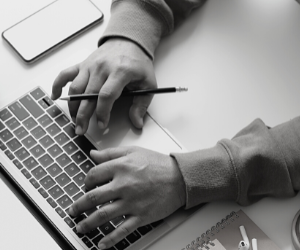 a black and white photo of a person working on a laptop