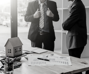 a black and white photo of two people consulting financial reports