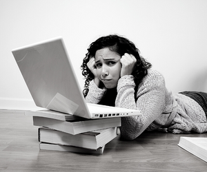 a small black and white photo of a concerned woman lying in front of her laptop while trying to solve accounting solution