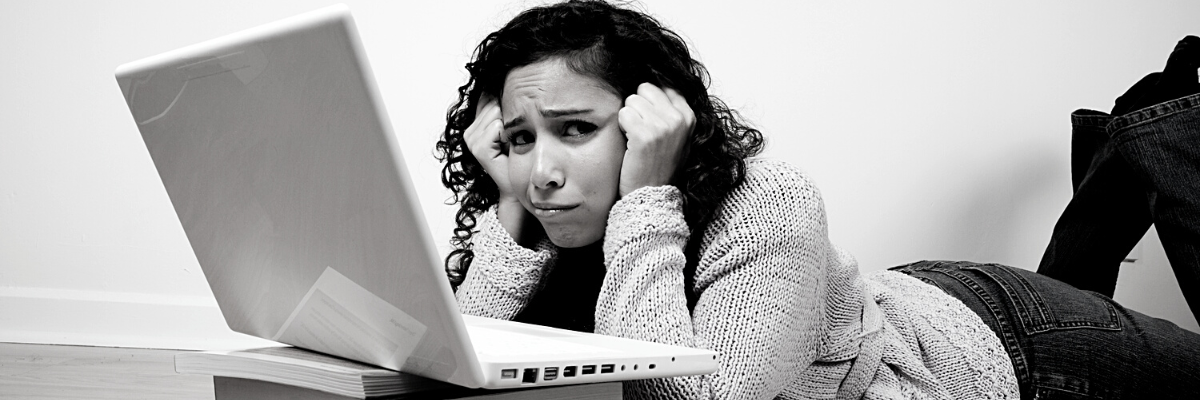 a black and white photo of a concerned woman lying in front of her laptop while trying to solve accounting solution