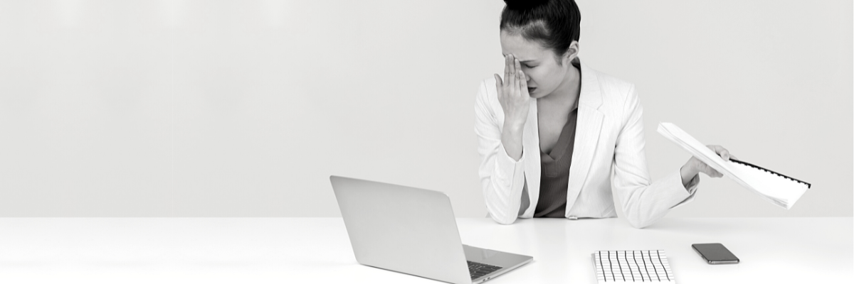 a black and white photo of a very tired woman sitting at a table in front of a laptop