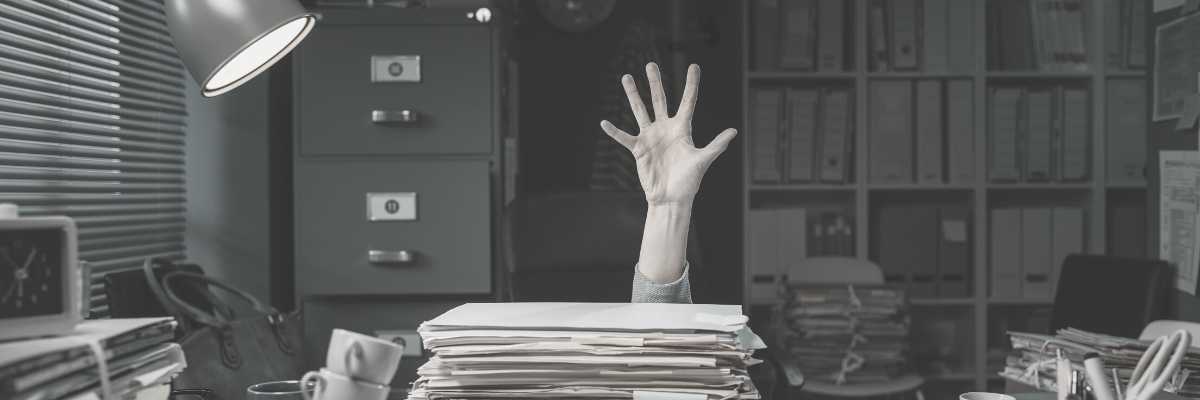 a landscape black and white photo of someone showingtheir hand above a load of files