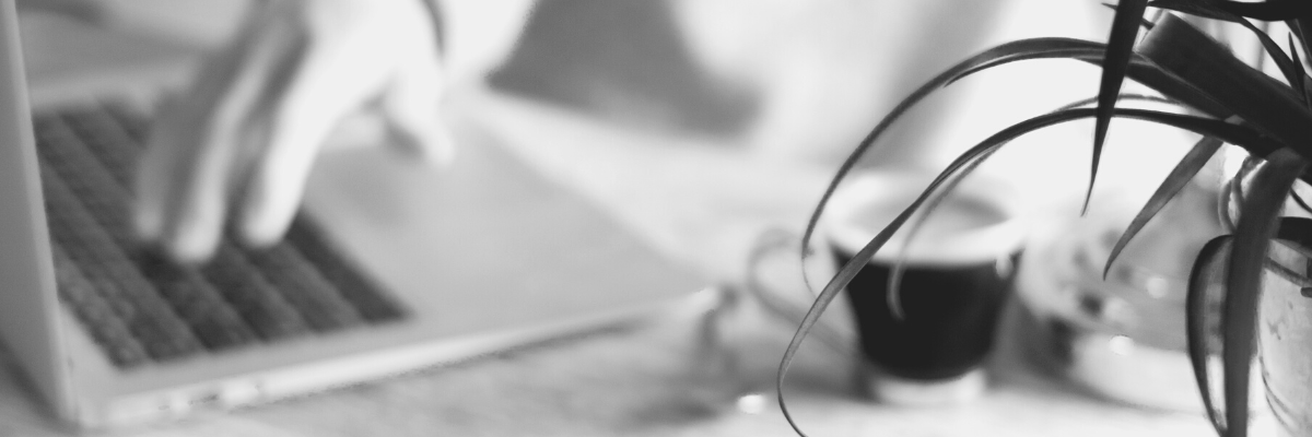 a black and white photo of working desk with a laptop and coffee