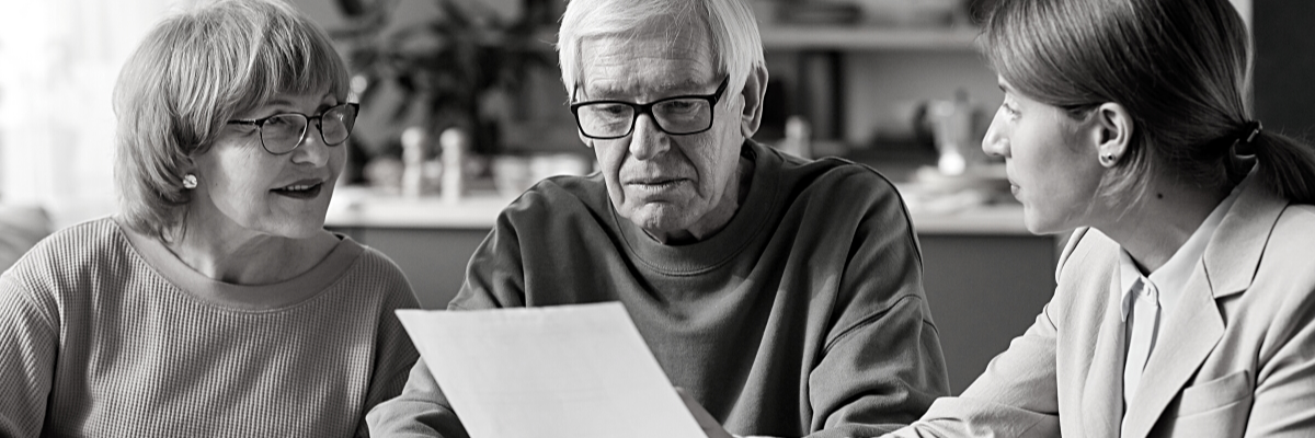 a landscape black and white photo of a financial consultant discussing retirement plans with some pensioners