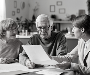 a black and white photo of a financial consultant discussing retirement plans with some pensioners