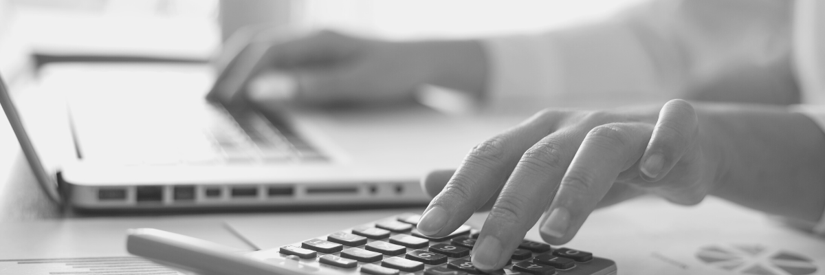 a black and white photo of an accountant working on their laptop and calculator original