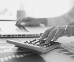 a black and white photo of an accountant working on their laptop and calculator