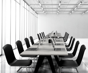 a black and white photo of a boardroom filled with laptops and chairs